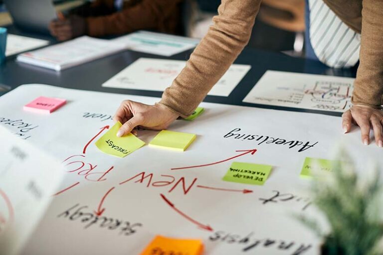 A woman is designing her small business plan on a big piece of paper.