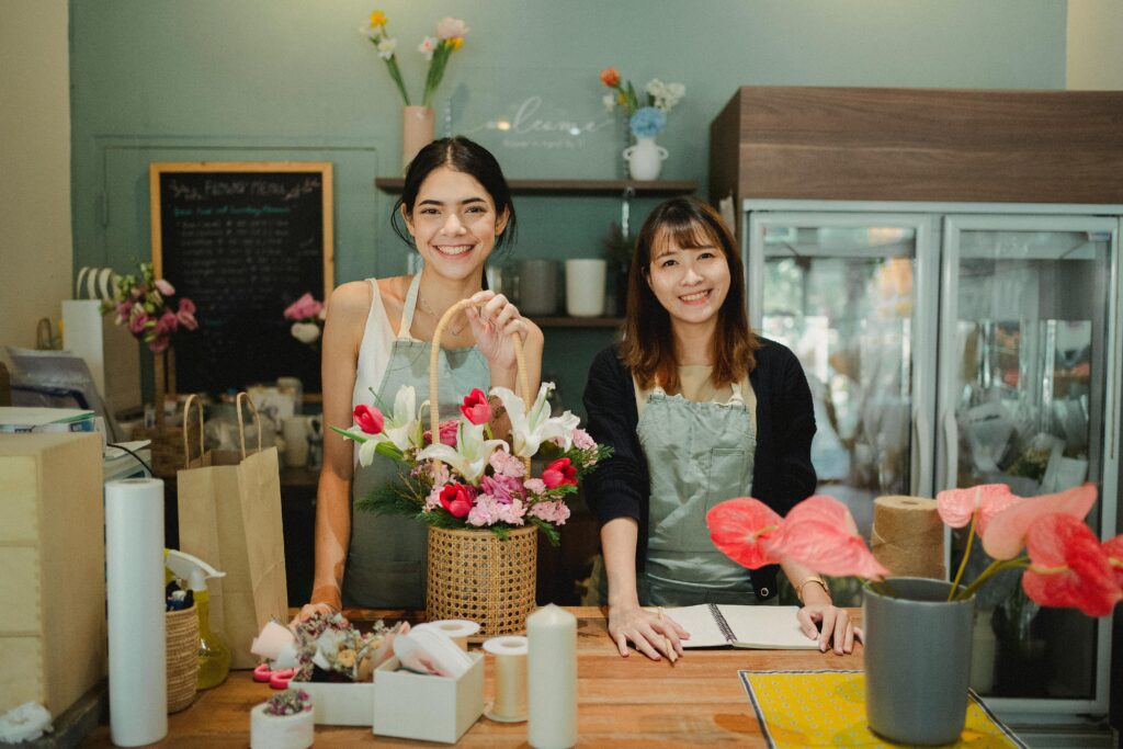 Smiling florists stand at a counter in a flower shop