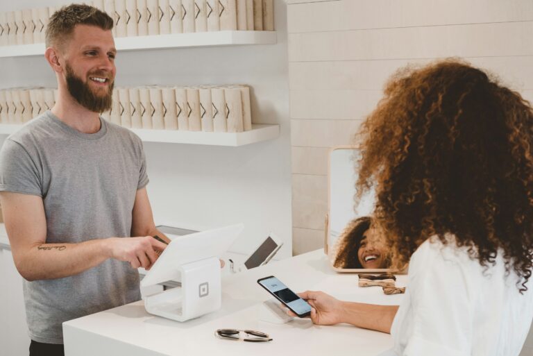 Man behind a store counter accepts digital wallet payment from woman